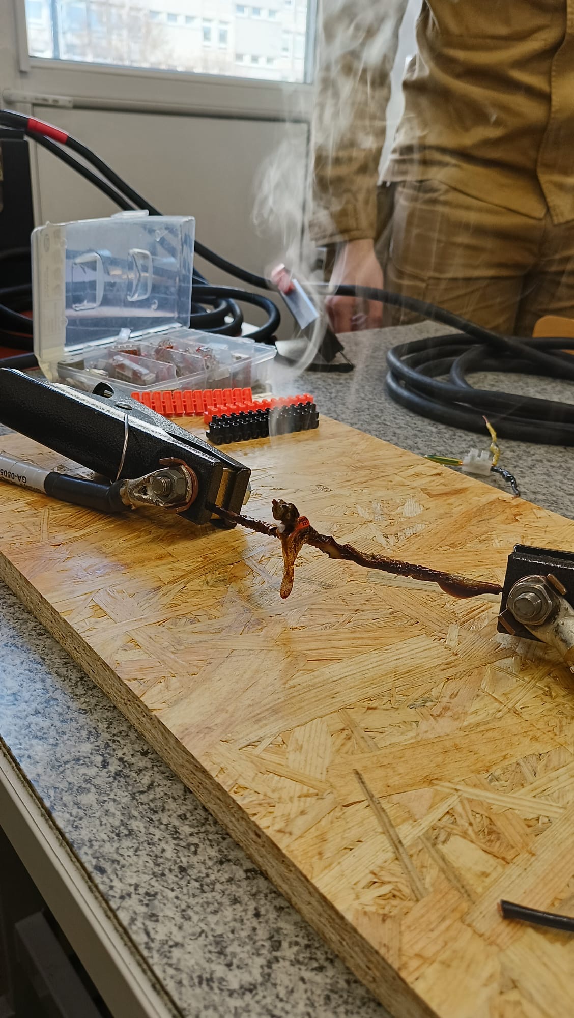 zdjęcie przedstawiające ćwiczenie dotyczące pomiaru temperatury/wykrywania pożaru - osoba z kamerą termowizyjną dokonuje pomiaru celując nią w dymiący się przewód