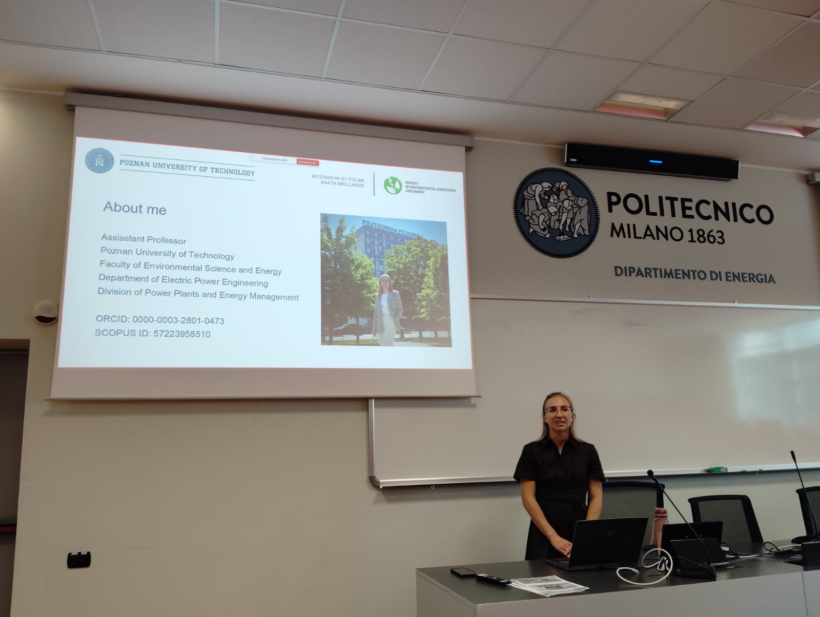 zdjęcie A. Mielcarek podczas prezentacji, po lewej widoczny ekran