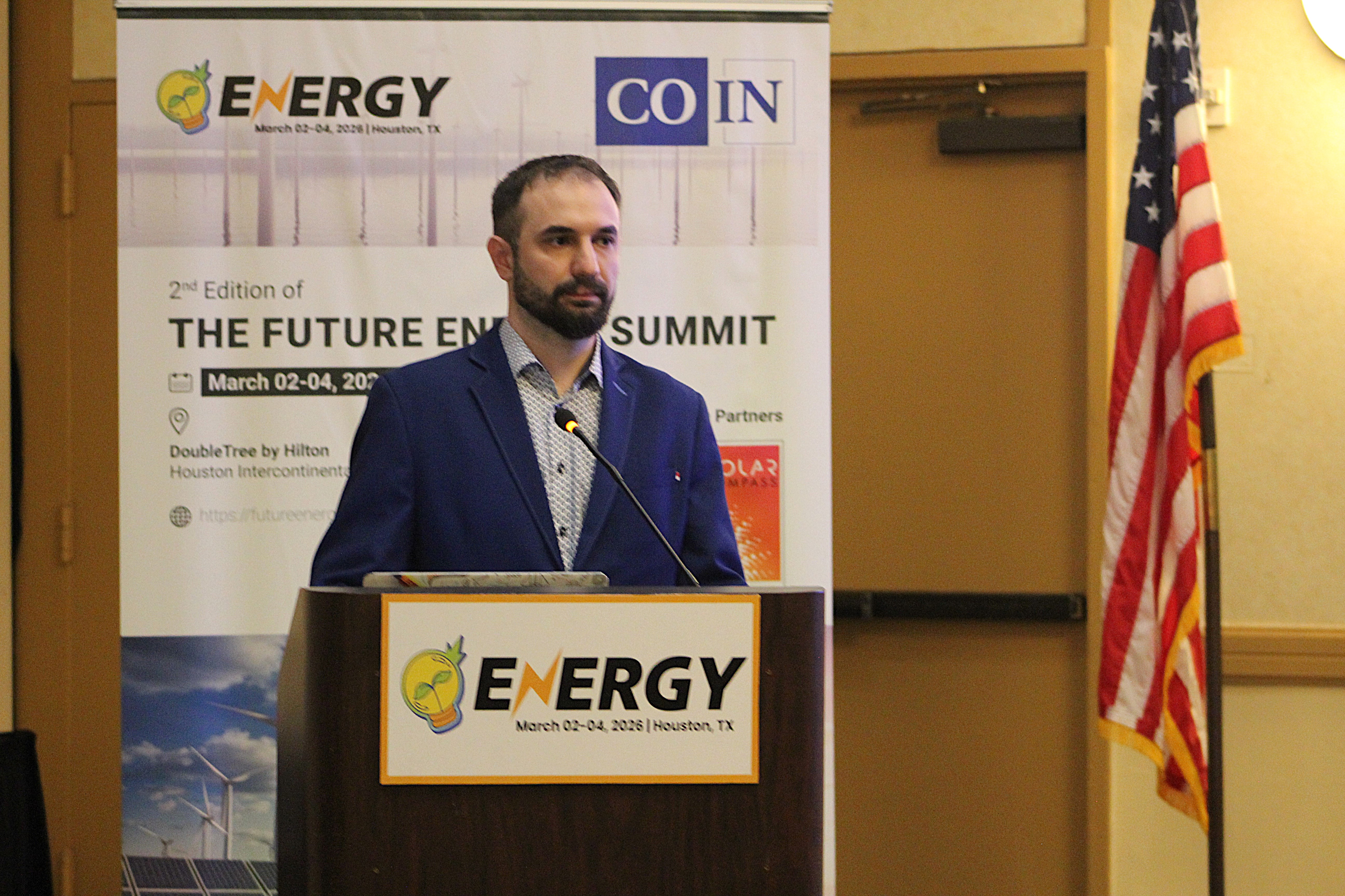 zdjęcie przedstawiające dr inż. K.Łowczowskiego podczas wystąpienia na konferencji (widoczny przy katedrze, za nim znajduje się plakat informujący o konferencji)