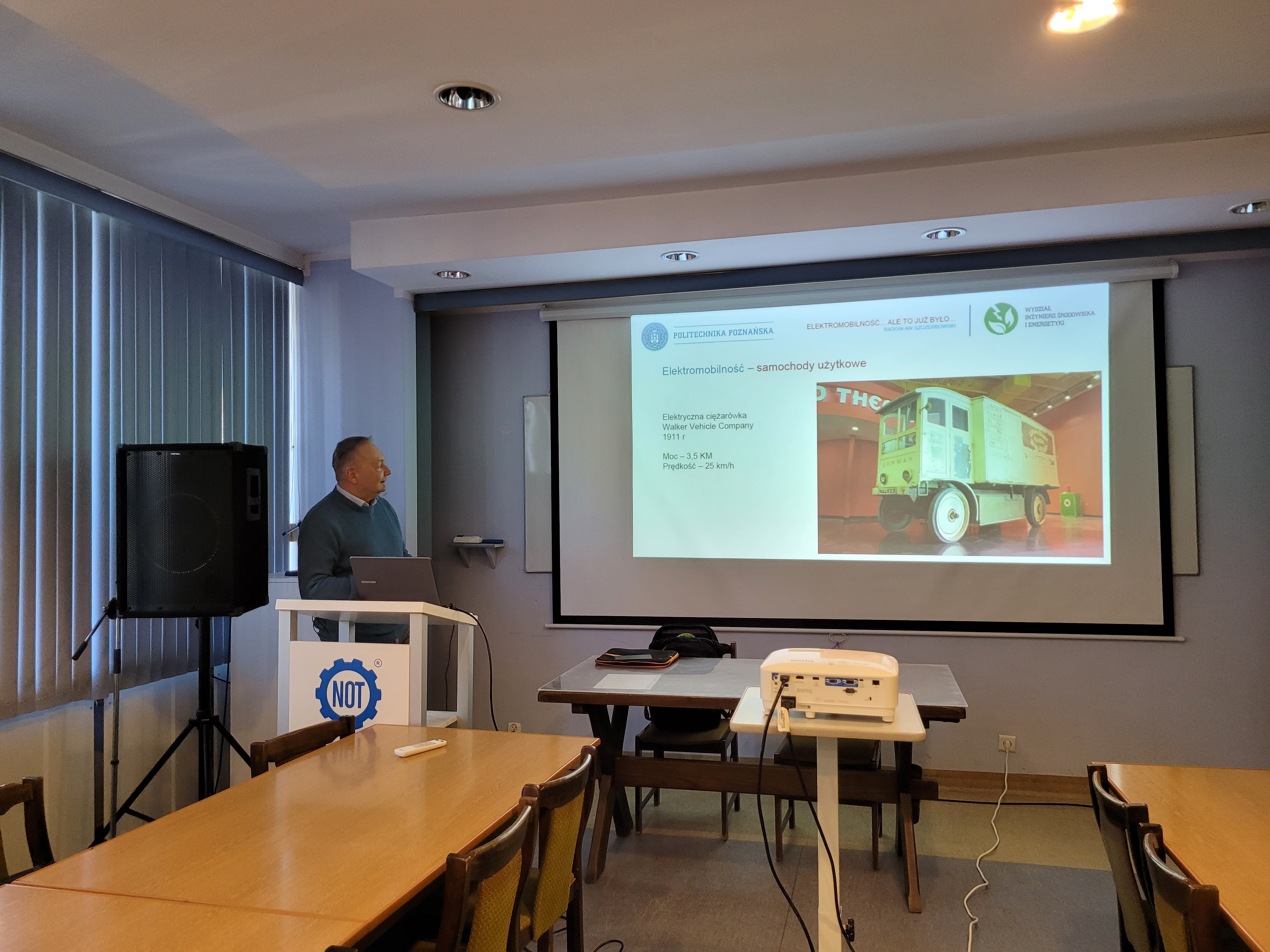 zdjęcie przedstawiające dr inż. R. Szczerbowskiego (z lewej) podczas wygłaszania referatu (opo prawej widoczny ekran z prezentacją)