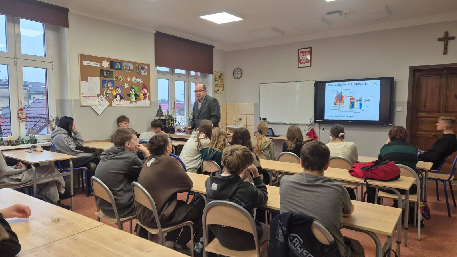 zdjęcie przedstawiające uczniów siedzących w ławkach , na środku klasy stoi prof. B. Ceran (inny kadr zdjęcia niz poprzedni)