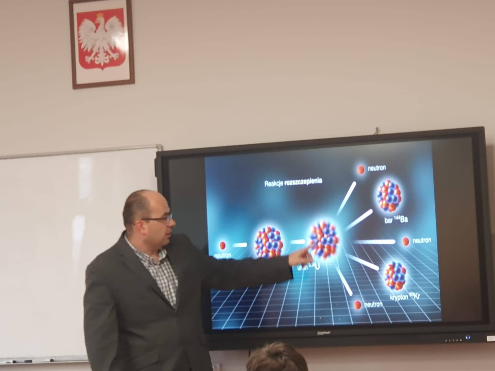 zdjęcie przedstawiające prof. B. Cerana przy ekranie, na którym wyświetlony jest schemat reakcji rozszczepienia