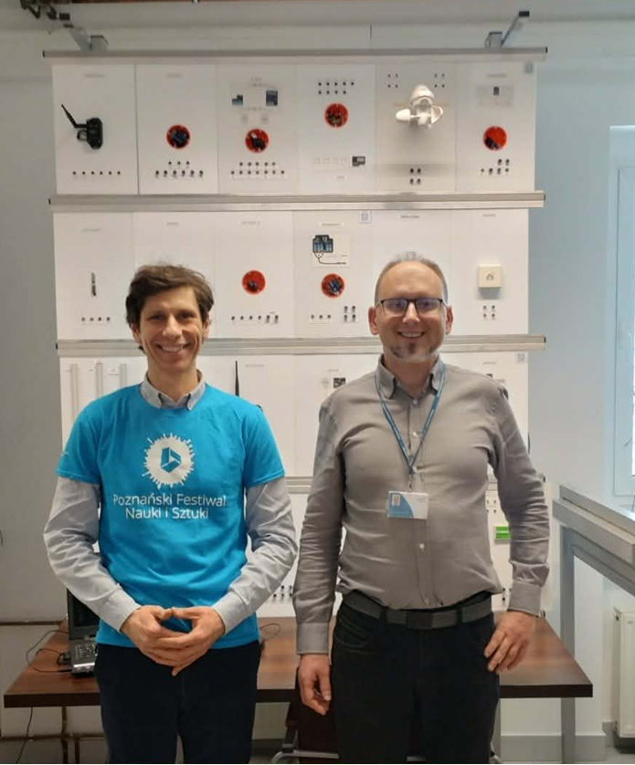 na zdjęciu po lewej widoczny mgr inż Józef Piechocki, z prawej dr inż. Krzysztof Dziarski. Panowie stoją w laboratorium inteligentnego budynku (widoczne w tle elementy systemu)