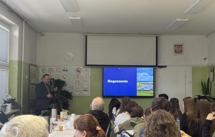 zdjęcie przedstawiające salę, w której odbywa się wykład dr inż. R.Szczerbowskiego (przedstwiony na zdjęciu po lewej stronie), z przodu widoczni uczestnicy konkursu, opiekunowie oraz zaproszeni gości