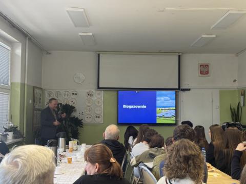 zdjęcie przedstawiające salę, w której odbywa się wykład dr inż. R.Szczerbowskiego (przedstwiony na zdjęciu po lewej stronie), z przodu widoczni uczestnicy konkursu, opiekunowie oraz zaproszeni gości